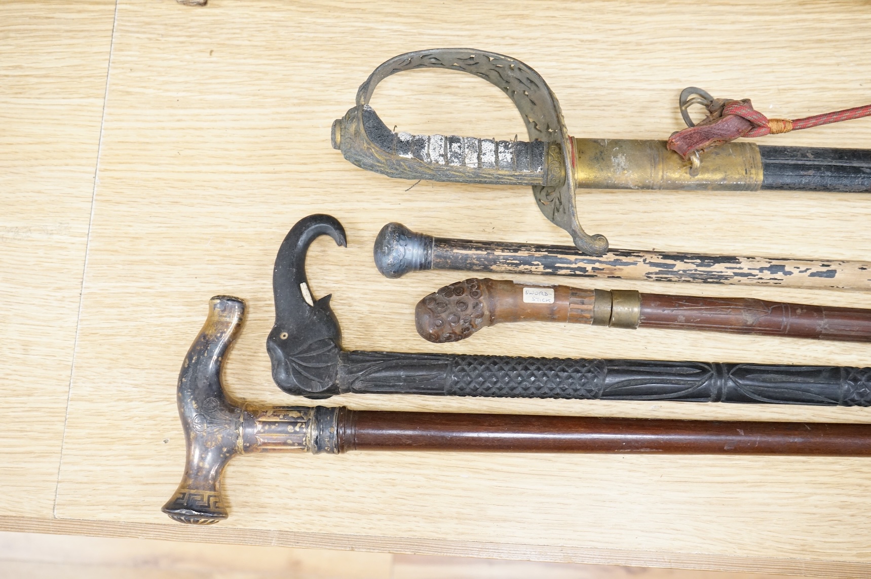 An officer’s sword, three walking sticks and an antique sword stick, longest walking stick 92cm long